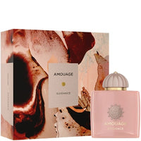 Amouage Guidance perfume bottle in soft pink with a gold cap, shown next to its matching outer box featuring a marbled abstract pattern in pink, brown, and beige tones.