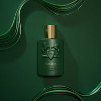 Parfums de Marly Haltane Eau de Parfum bottle on a deep green background with flowing ribbon accents and gold cap.