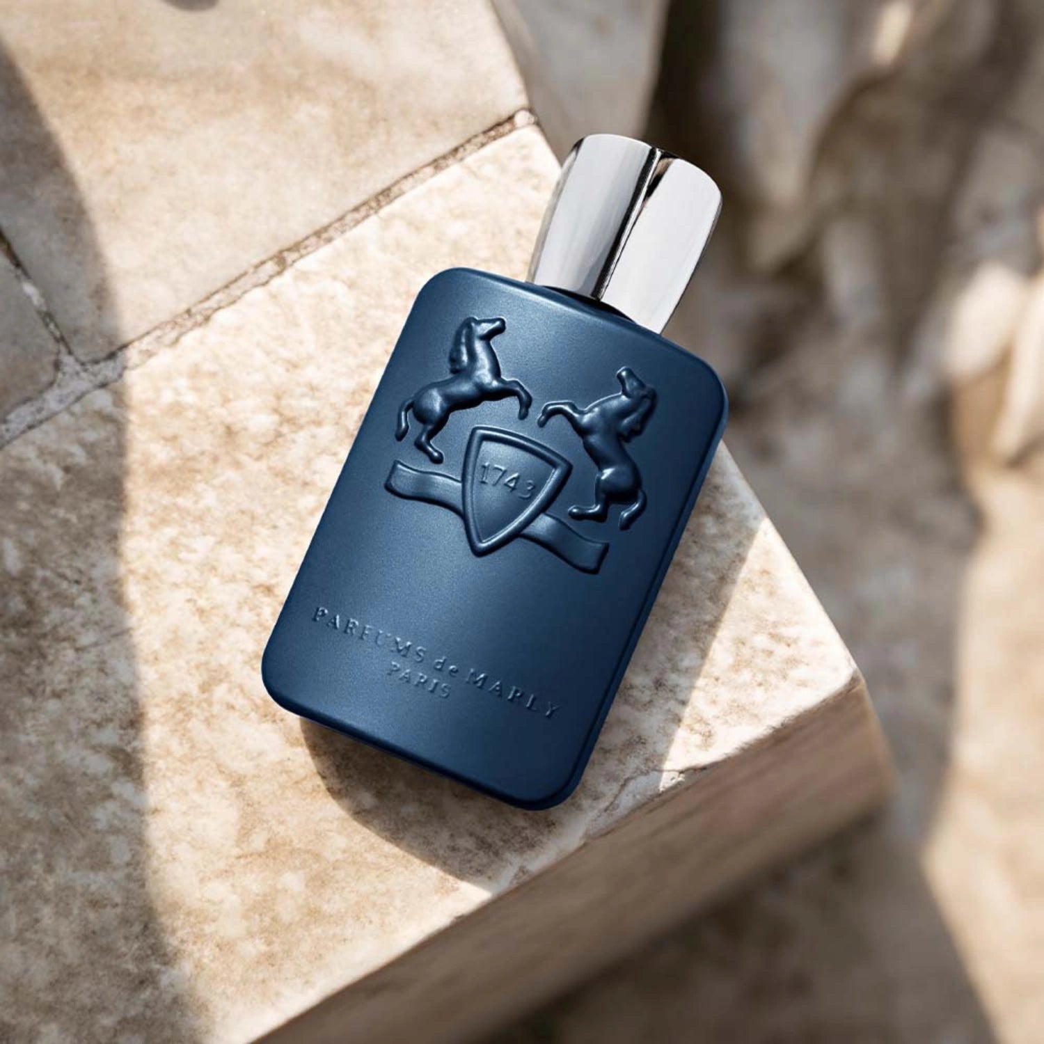 Parfums de Marly Layton Eau de Parfum bottle with a matte deep navy blue finish and silver cap displayed on a light stone surface.