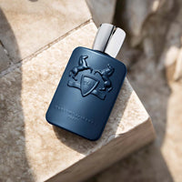 Parfums de Marly Layton Eau de Parfum bottle with a matte deep navy blue finish and silver cap displayed on a light stone surface.