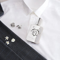 Parfums de Marly Pegasus Eau de Parfum styled on a crisp white dress shirt with a tailored suit jacket, cufflinks, ring and white flowers, highlighting its refined masculine aesthetic.